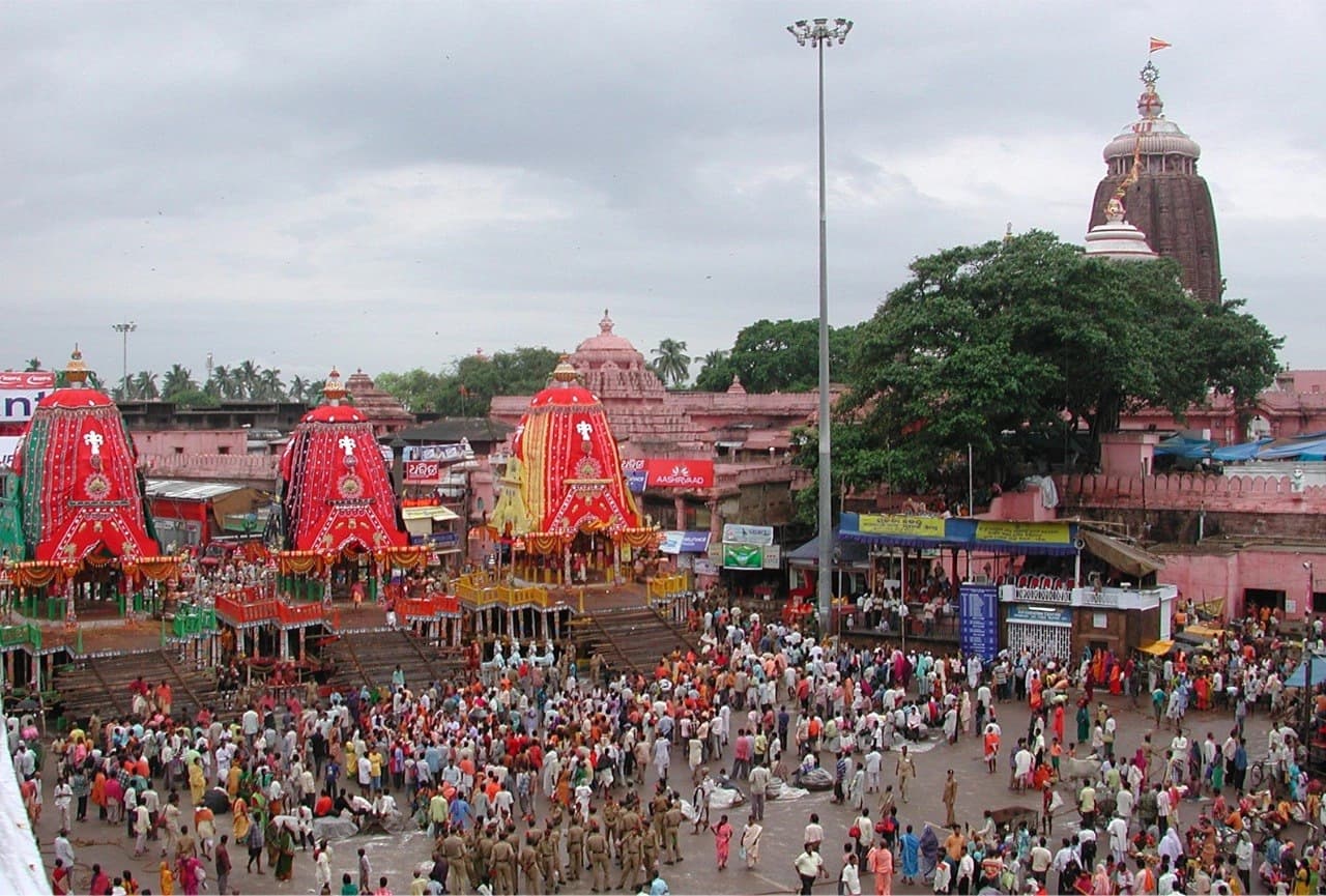Three Rath Yatra chariots lined before the Jagannath Temple, Puri, with crowds on the Grand Road